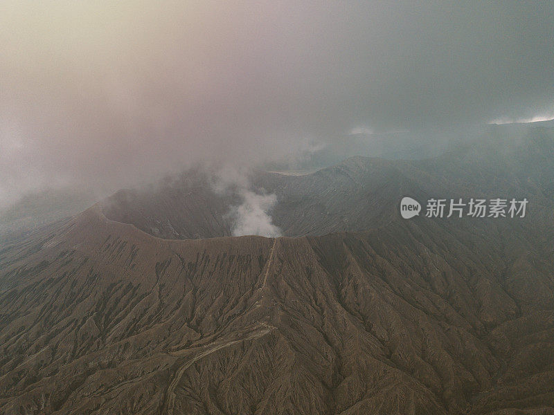 无人机鸟瞰图的Bromo火山口边缘与蒸汽在Bromo山国家公园在Cemoro Lawang村-东爪哇，印度尼西亚，亚洲。旅游目的地冒险的自然概念